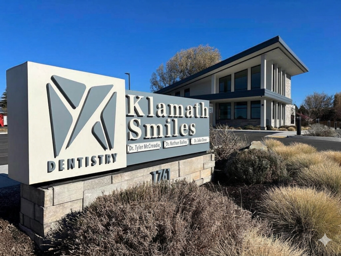 Klamath smiles dental sign showing the names of Dr. Tyler McCreadie, Dr. Nathan Bailey, and Dr. Jake Dove. The Klamath Smiles building is in the background.